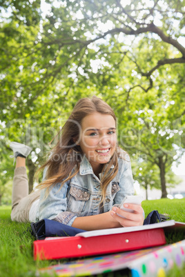 Young happy student lying on the grass sending a text Young happy student lying on the grass sending a text