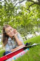 Young happy student lying on the grass on the phone