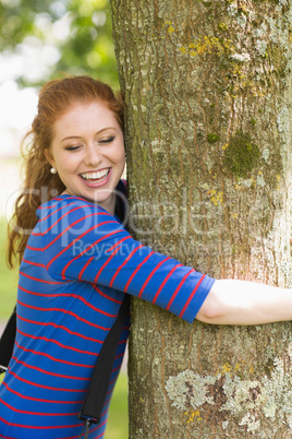 Laughing redhead hugging a tree