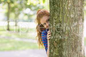 Cute redhead hiding behind a tree