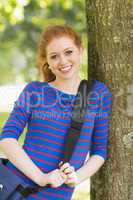 Cheerful student leaning against a tree