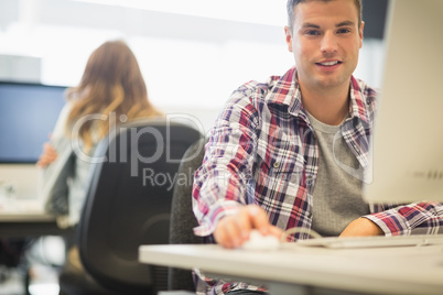 Cheerful student looking at camera in the computer room