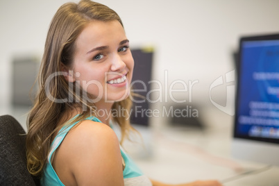 Pretty student smiling at camera in the computer room