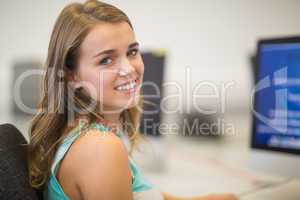 Pretty student smiling at camera in the computer room