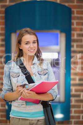 Student standing smiling at camera at the atm