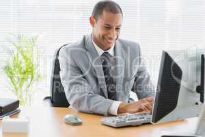 Smiling businessman using computer at office