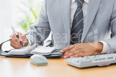 Mid section of a businessman writing in diary