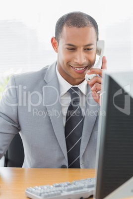 Businessman using computer and phone at office desk