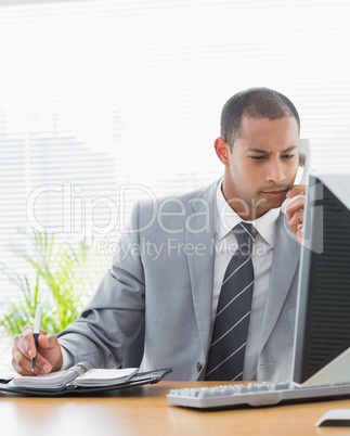 Businessman using computer and phone at office