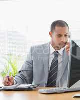 Businessman using computer and phone at office