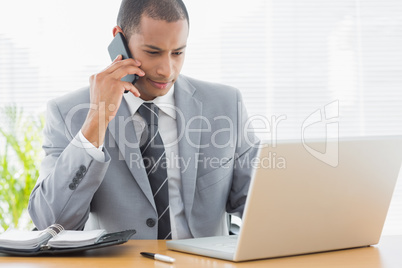 Businessman using laptop and cellphone at office