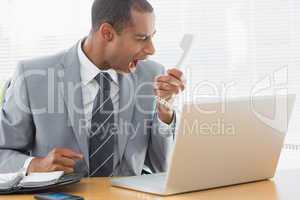 Businessman shouting into the phone at office
