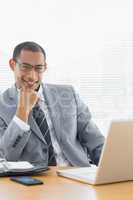 Confident businessman with laptop at office desk