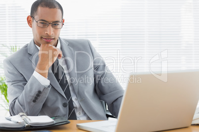 Confident businessman with laptop at office desk