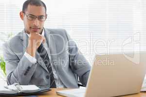 Confident businessman with laptop at office desk