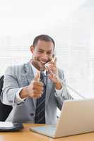 Businessman gesturing thumbs up while on call at desk