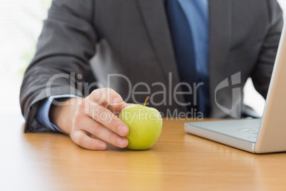 Smartly dressed businessman with laptop and apple at office