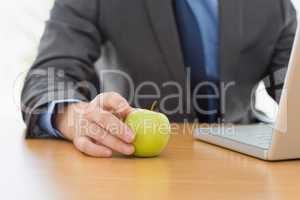 Smartly dressed businessman with laptop and apple at office