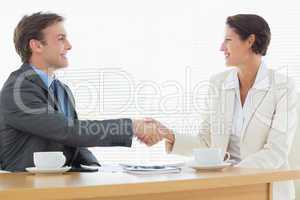 Smartly dressed couple shaking hands in business meeting
