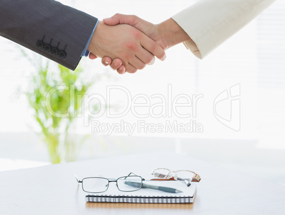 Shaking hands over eye glasses and diary after business meeting