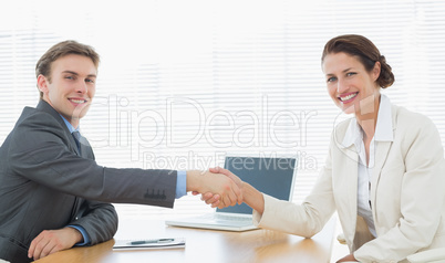 Business couple shaking hands in office