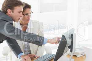 Business couple using computer at office desk