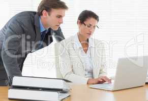 Business couple using laptop at office desk