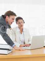 Business couple using laptop at office desk