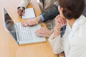 Business colleagues using laptop at desk