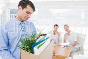 Businessman carrying his belongings with colleagues in backgroun