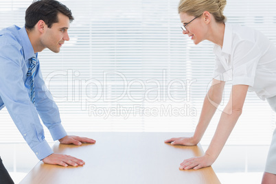 Smiling business couple looking at each other with palms at desk