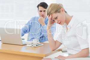 Upset businesswoman with man working on laptop