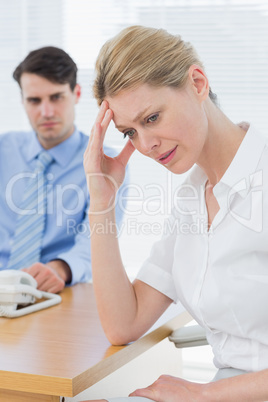 Upset businesswoman with man working on laptop