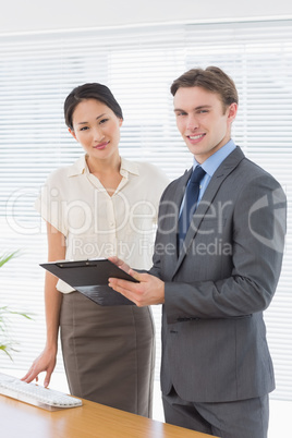 Confident business colleagues with clipboard at office