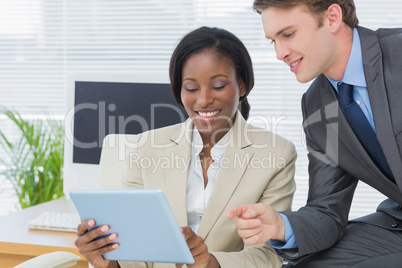 Colleagues using digital tablet in office