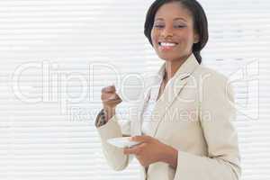 Elegant smiling businesswoman with a cup of tea in office