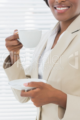 Mid section of smiling businesswoman with a cup of tea