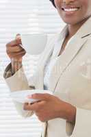 Mid section of smiling businesswoman with a cup of tea