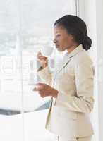 Businesswoman with tea cup looking through office window