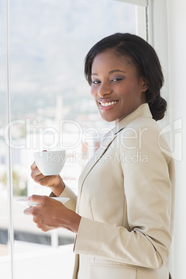 Elegant smiling businesswoman with a cup of tea in office