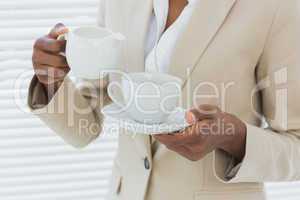 Mid section of elegant businesswoman with tea cup