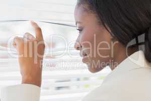 Businesswoman peeking through blinds