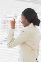 Businesswoman peeking through blinds in office
