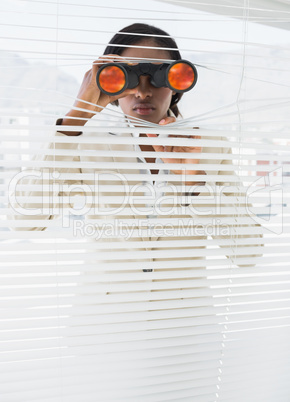 Businesswoman peeking with binoculars through blinds