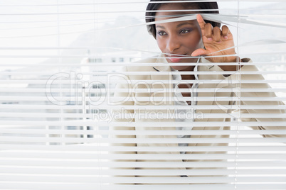 Businesswoman peeking through blinds