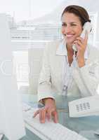 Smiling businesswoman using computer and phone