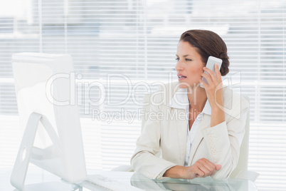 Businesswoman using computer and cellphone at desk