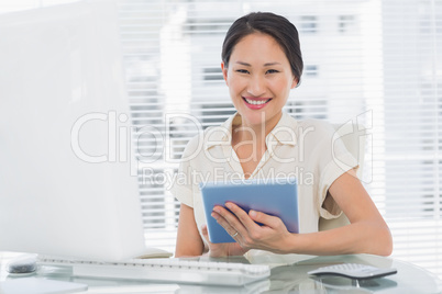 Smiling businesswoman using digital tablet at desk