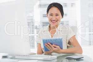 Smiling businesswoman using digital tablet at desk