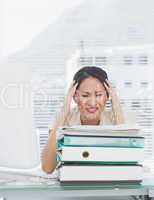 Angry businesswoman with stack of folders at desk